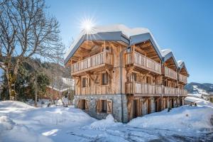 uma cabana de madeira na neve com terrenos cobertos de neve em Moulin Chalets Les Gets - by EMERALD STAY em Les Gets