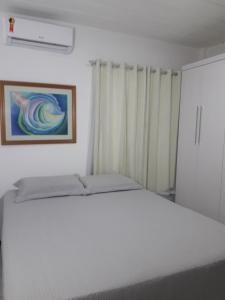 サルバドールにあるApartamento Stela Maris Praia e Aeroportoの白いベッドと壁に絵画が飾られたベッドルーム1室