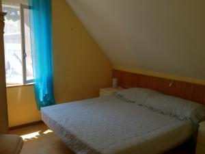 リニャーノ・サッビアドーロにあるVillino Colussiのベッドルーム1室(青いカーテン、窓付)