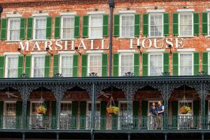 two people standing on a balcony in front of a maritzel house at The Marshall House, Historic Inns of Savannah Collection in Savannah