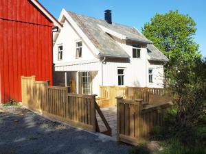 uma casa branca com uma cerca de madeira ao lado de um celeiro vermelho em Kårstua - Austrått Agroturisme em Austrått