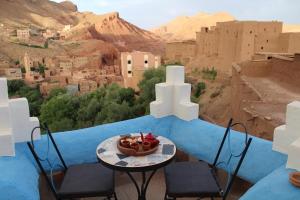 a table and chairs with a bowl of fruit on a balcony at Labyrinth Kasbah Dades in Aït Ben Ali