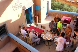 Labyrinth Kasbah Dades في Aït Ben Ali: مجموعة من الناس يجلسون على طاولة في مطعم