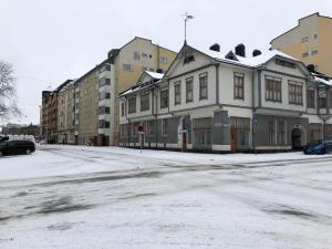 a snow covered street with a white house and buildings at City Apartments Turku - 1 Bedroom Apartment with private sauna in Turku
