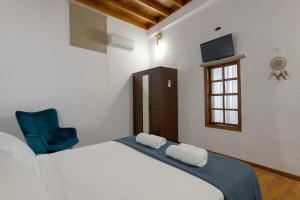 a bedroom with a bed and a blue chair at RUSTIC SELF-INN in Rhodes Town