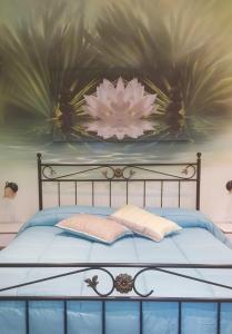 a bed with a blue and white bedspread and a painting on the wall at Il Mondo B&B in Fiumicino