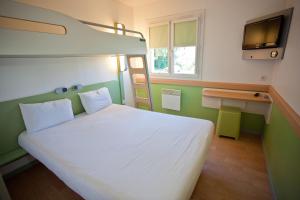 - une chambre avec un lit blanc et une télévision dans l'établissement ibis budget Marne la Vallée, à Saint-Thibault-des-Vignes