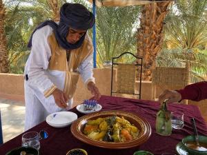 a woman standing at a table with a plate of food at Ecolodge du Draa in Ouled Otmane