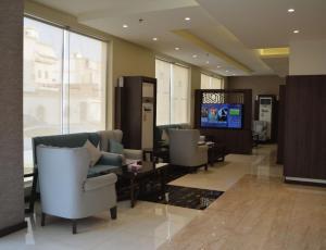 a lobby with couches and chairs and a television at Hmm Serviced Apartments in Al Kura