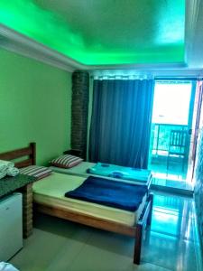 Recanto do Mergulhão في ماسيو: غرفة نوم مع سرير كبير مع ضوء أخضر