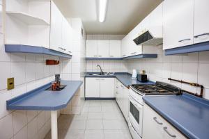 una cocina con armarios blancos y encimeras azules en Tempo Rent Apart Hotel, en Santiago
