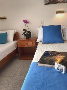 een hotelkamer met twee bedden en een boek op het bed bij Cape Blue Apartments in Paralía Skotínis