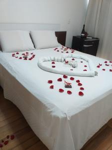 a white bed with red roses on it at Pousada Amelia in Urubici