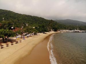 a beach with chairs and people on the sand and water at Pousada Agua Viva in Abraão
