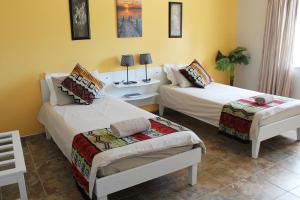 two beds in a room with yellow walls at Omaruru Guesthouse in Omaruru