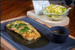 a blue plate with a piece of fish and a bowl of salad at Villa Nogal Hotel Boutique & Vista in San Sebastián del Oeste