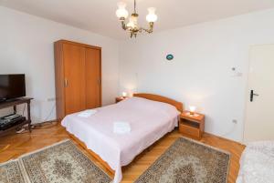 1 Schlafzimmer mit einem weißen Bett und einem TV in der Unterkunft Apartment Linda in Primošten