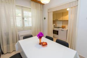 einen weißen Esstisch mit einer Blumenvase darauf in der Unterkunft Apartment Linda in Primošten