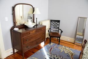 baño con tocador con espejo y silla en Maine Victorian Mansion, en Saco