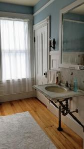 baño con lavabo, espejo y ventana en Maine Victorian Mansion, en Saco