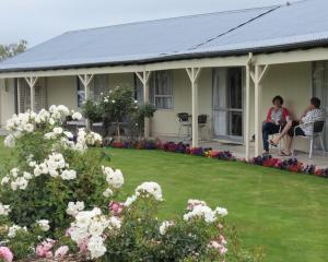 two people sitting on the porch of a house with flowers at Culverden Court Motel in Culverden