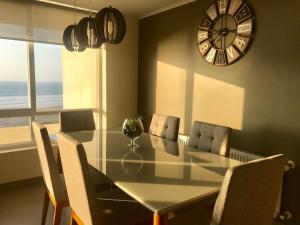 a dining room table with chairs and a clock on the wall at Ensueños en Laguna Del Mar in La Serena