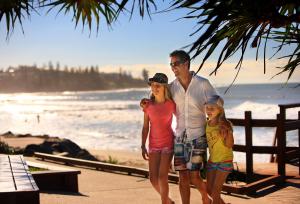 a man and a woman standing next to each other on a beach at Rumba Beach Resort in Caloundra