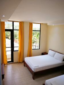 een slaapkamer met een wit bed en 2 ramen bij La Bocana in Tonsupa