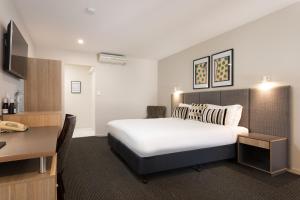a hotel room with a bed, table and a lamp at Brisbane International Virginia in Brisbane