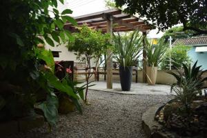 a garden with potted plants and a wooden pergola at Pousada Vovo Valdir in Itapema