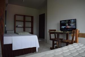 a room with a bed and a table with a television at Pousada Vovo Valdir in Itapema