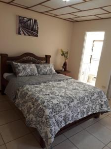 a bedroom with a bed with a gray and white comforter at Kubo Apartment in Alajuela