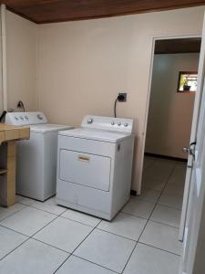 een wasruimte met 2 wasmachines en een deur naar een andere kamer bij Kubo Apartment in Alajuela