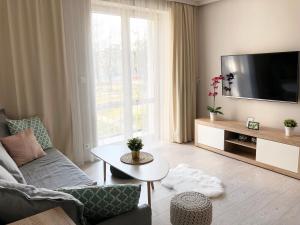 ein Wohnzimmer mit einem Sofa und einem TV in der Unterkunft Ozarowska 77 - 1BR by Homeprime in Warschau