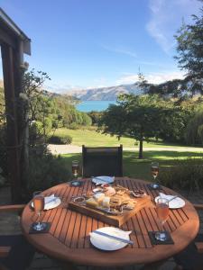 un tavolo in legno con un piatto di cibo e bicchieri di vino di Cherrywood Cottage ad Akaroa