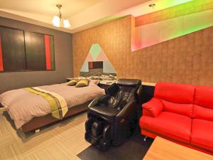 a bedroom with a bed and a red couch at Hotel Sen (Love Hotel) in Mizumaki