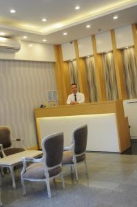 a man standing behind a counter in a room with chairs at Hotel Kabacam Aydin in Aydın