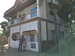 Ein Mann und eine Frau stehen vor einem Haus in der Unterkunft Chona and Christophe Guesthouse - Masbate in Masbate