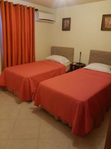two beds in a room with red curtains at Breezy Apts in Saint Philip