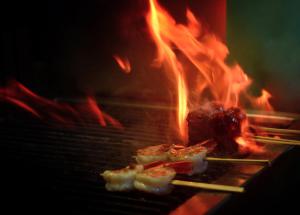 a group of food cooking on a grill with flames at Capella Ubud, Bali in Ubud