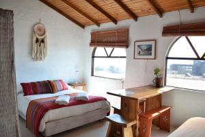 a bedroom with a bed and a desk and windows at Conviento de Lobos in Pichilemu