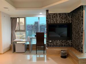 uma sala de estar com uma televisão e uma mesa com uma cadeira em E Lim Hotel em Zhongli