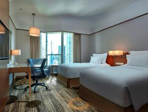 a hotel room with two beds and a desk at Pullman Kuala Lumpur City Centre Hotel & Residences in Kuala Lumpur