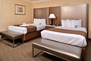a hotel room with two beds and a table at Best Western Hollywood Plaza Inn Hotel - Hollywood Walk of Fame LA in Los Angeles