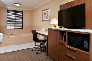 a bathroom with a television and a desk with a chair at Best Western Hollywood Plaza Inn Hotel - Hollywood Walk of Fame LA in Los Angeles