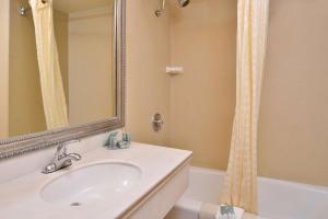 a bathroom with a sink and a mirror and a tub at Best Western Hollywood Plaza Inn Hotel - Hollywood Walk of Fame LA in Los Angeles
