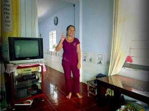 una donna in piedi in un soggiorno con TV di Bai Huong homestay a Hoi An