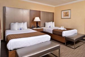 a hotel room with two beds and a chair at Best Western Hollywood Plaza Inn Hotel - Hollywood Walk of Fame LA in Los Angeles