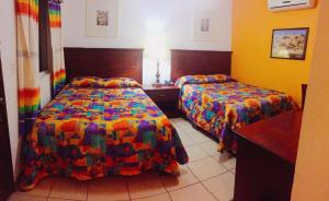 a hotel room with two beds and two tables at Hotel Paquime in Nuevo Casas Grandes