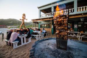 a group of people sitting at tables in front of a building at Pili Pili Beach Cabanas in Sedgefield
